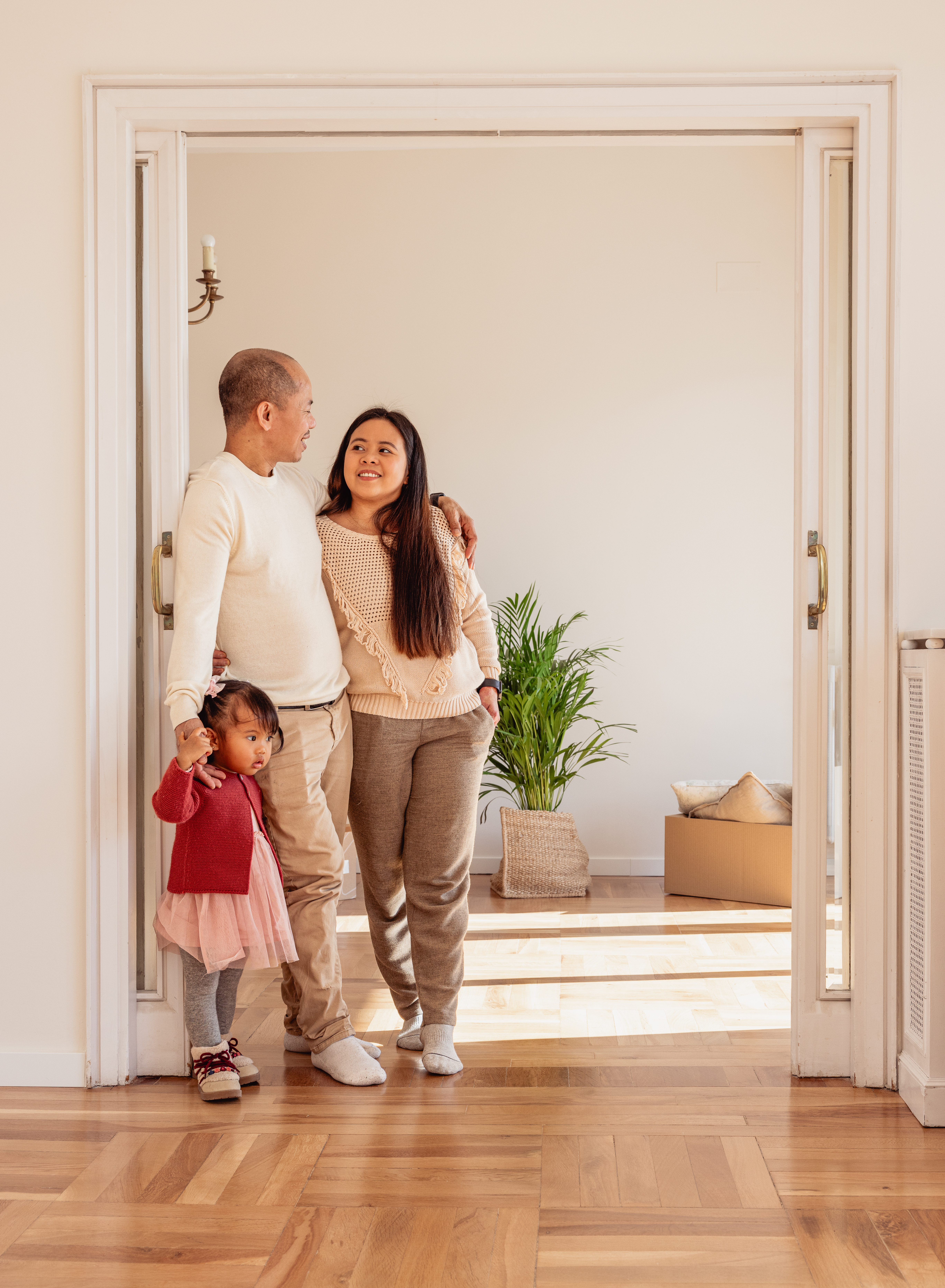 Asian parents and baby standing together in their new home